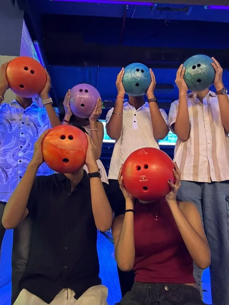 Friends holding bowling balls up at a bowling night